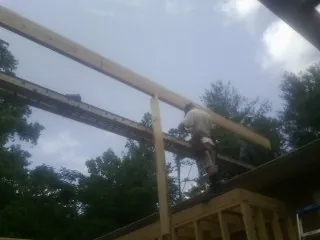 Carpenter setting a ridge beam over a new addition frame — Ice Dam Removal by Roofing Brothers in Ludowici