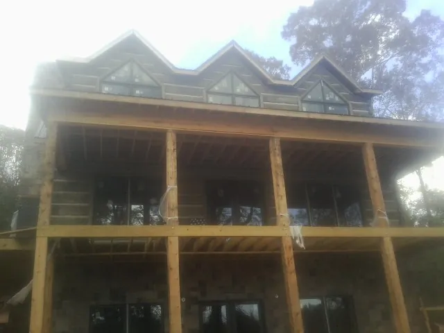 Dormers and porch framing on a large log home under construction — Roof Coating work by our crew in Ludowici