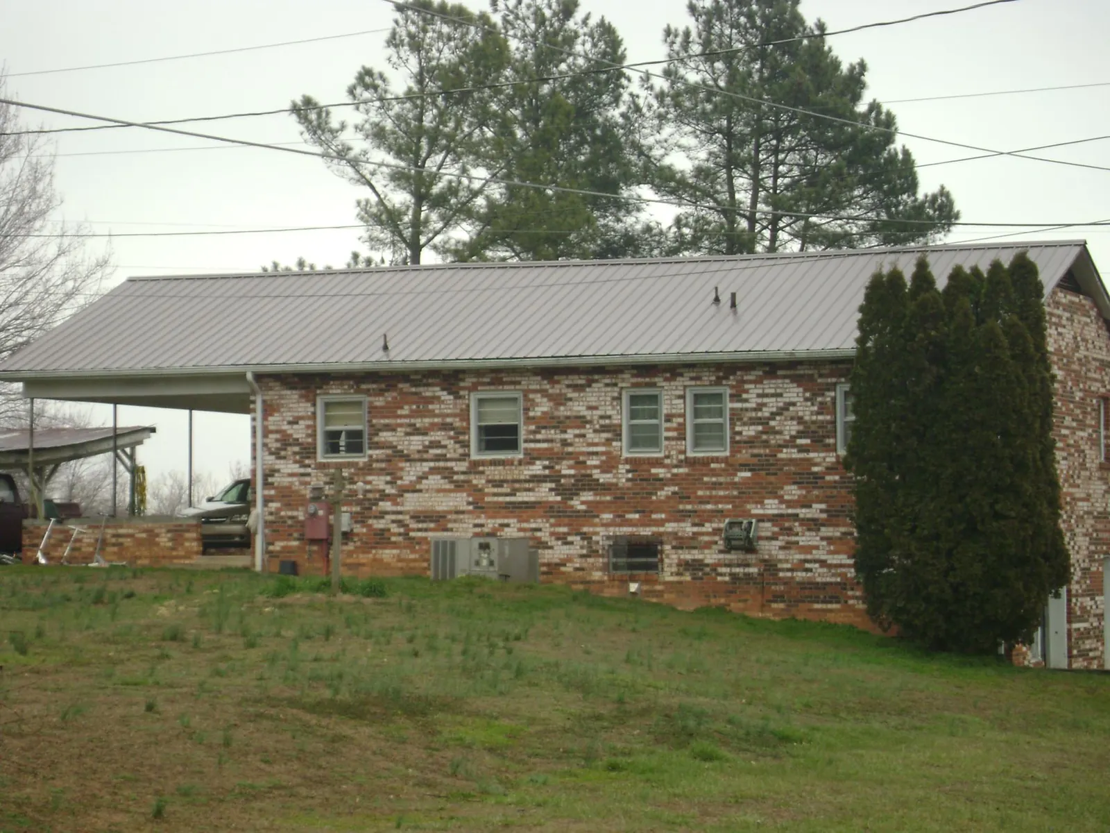 Gray metal roof on a brick split level home with a carport in Ludowici
