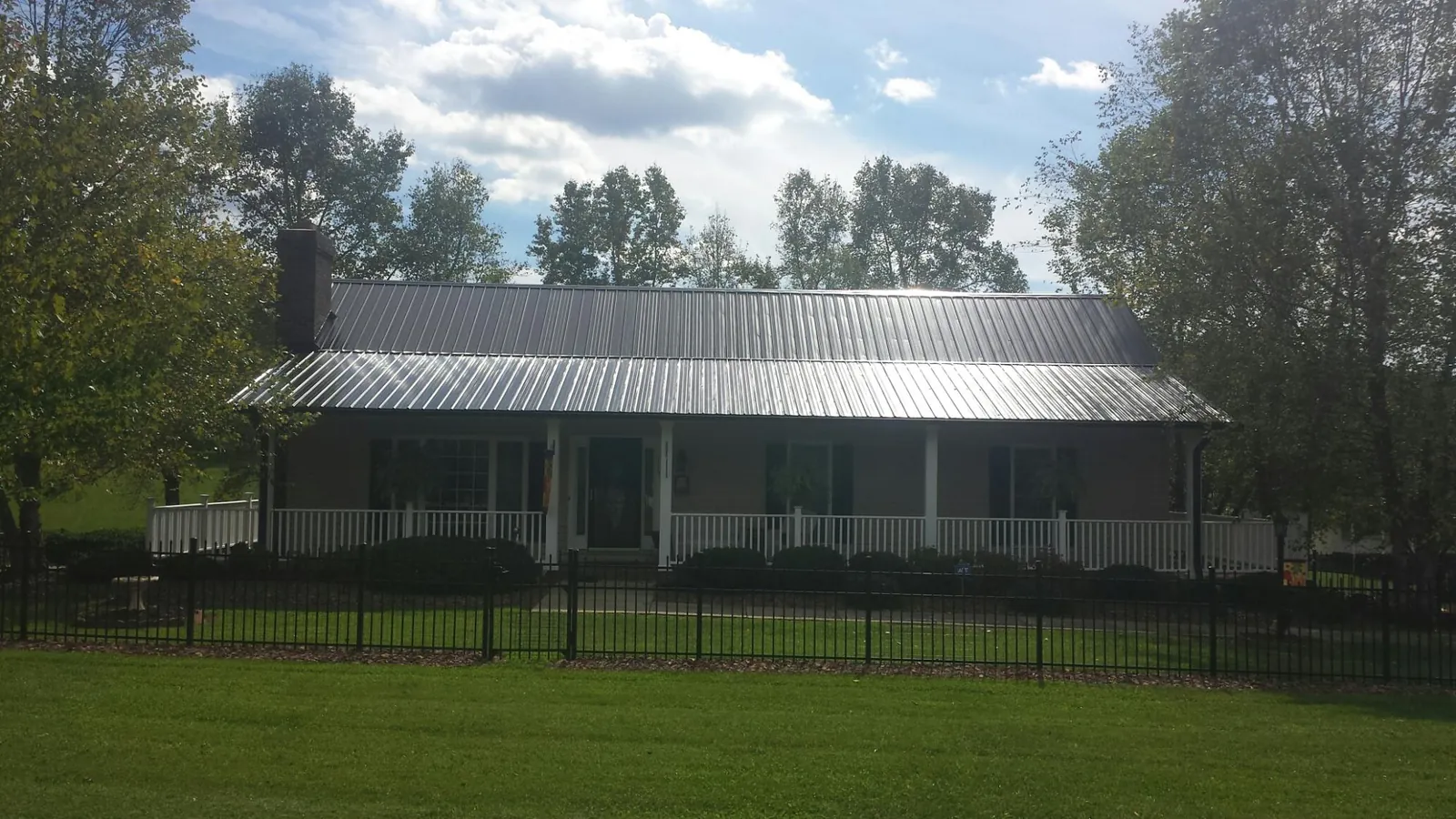 Gray metal roof on a brick ranch with a full width front porch — Gutter Guard Installation work by our crew in Ludowici