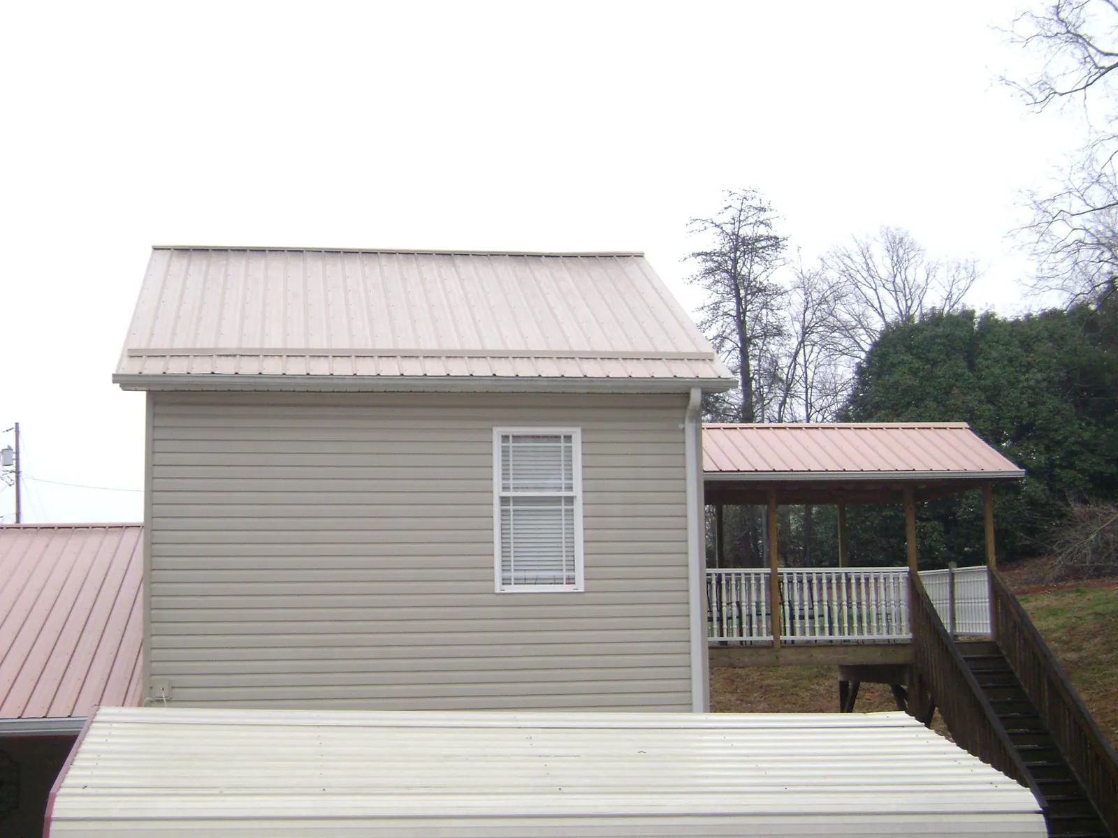 Tan metal roofs on a two story addition and attached porch, from a Roof Replacement job in Ludowici