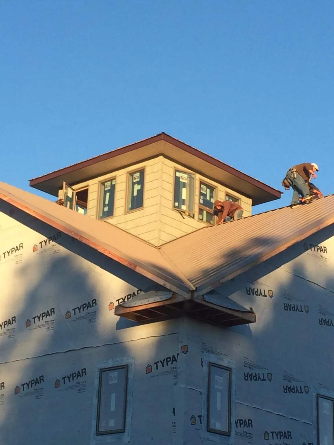 Roofers working around a rooftop cupola on a new metal roof at sunset — Roof Waterproofing in Ludowici by Roofing Brothers